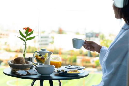 a person holding a cup of coffee and a table of food at City Park Hôtel in Casablanca