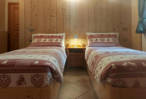 a bedroom with two beds and a table with a lamp at Baita al Pian in Bormio