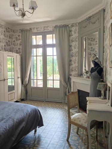 a woman in a bedroom with a mirror and a bed at Le Cottage des chats in Beaulieu-sur-Loire