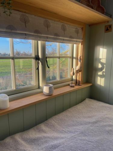 a bedroom with two windows and a bed in it at Happy Place Shepherds Hut in Bishops Tachbrook