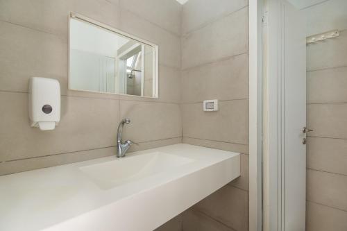 a white bathroom with a sink and a mirror at SPNI Golan Field School in Qasrîne