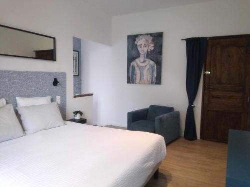 a bedroom with a bed and a chair and a painting at Les feuillets de la Buire in Monteux