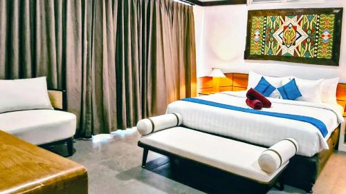 a bedroom with a bed and a chair and a couch at The Trawangan Resort in Gili Trawangan