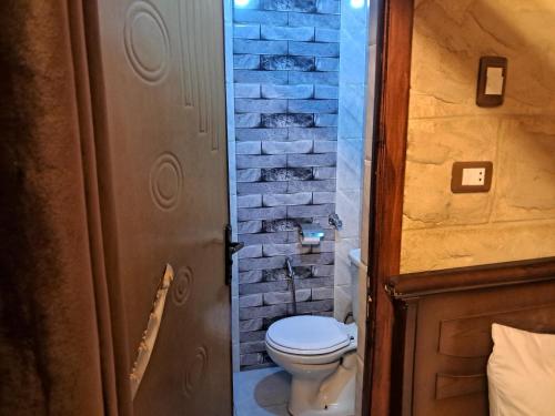 a bathroom with a toilet and a brick wall at Labib Guest house in Aswan