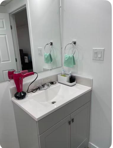 a white bathroom with a sink and a mirror at Ubbies place in Regina