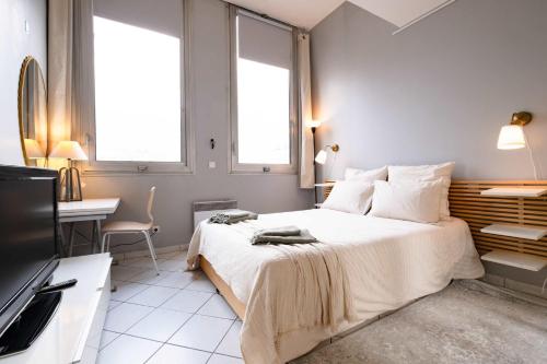 a bedroom with a bed and a desk and two windows at Loft Duplex Terrasse View on Paris in Paris