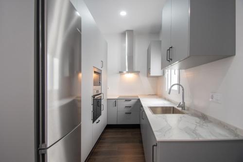 a kitchen with white cabinets and a stainless steel refrigerator at Zambra en Cádiz in Cádiz