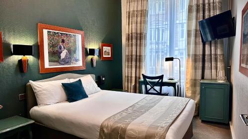 a bedroom with a bed and a desk and a window at Hotel De La Paix in Lille