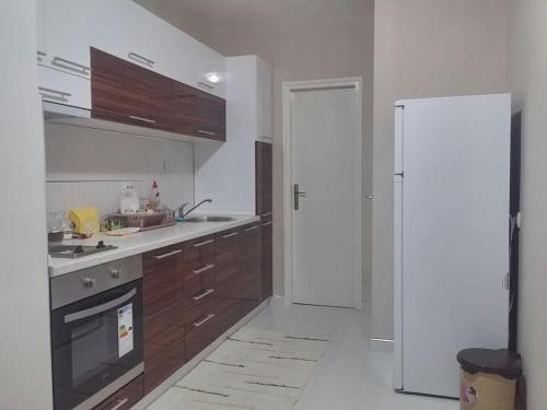a kitchen with a white refrigerator and wooden cabinets at Apartman Sweet dreams 1 in Niš