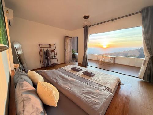 a bedroom with a bed and a large window at ไร่ชาอาโซ -ที่พักดอยช้าง in Ban Huai Khai