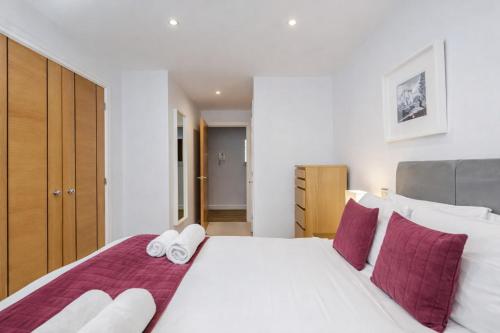 a bedroom with a large white bed with purple pillows at Roomspace Serviced Apartments - Abbot's Yard in Guildford