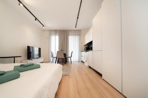 a white bedroom with two beds and a kitchen at Luxury Studio in the Heart of Limassol in Limassol