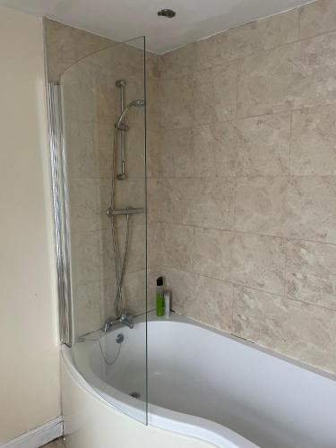 a bath tub with a glass shower in a bathroom at Babo Bolton room en suite in Farnworth