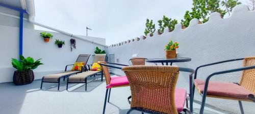 a patio with chairs and tables and a white wall at VelenaRubia in Vélez-Málaga