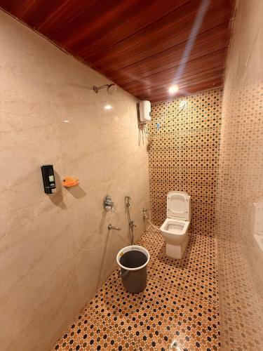 a bathroom with a toilet and a bucket at Capital Stay Inn in Vijayawāda