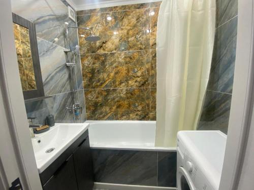 a bathroom with a shower and a tub and a sink at Elegant Home Stepnoy in Karagandy
