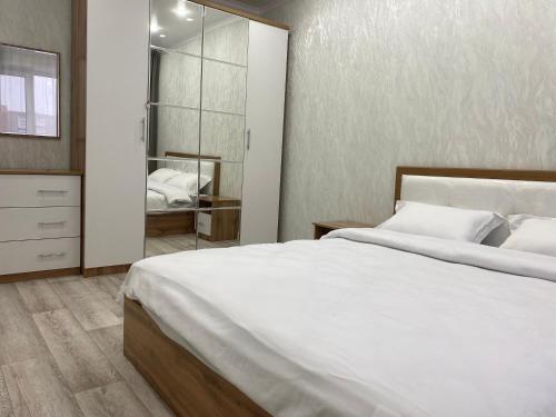 a bedroom with a large white bed and a mirror at Elegant Home Stepnoy in Karagandy