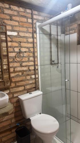 a bathroom with a toilet and a glass shower at Recanto Nativos in Garopaba