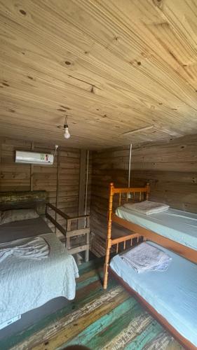 a room with three beds in a wooden cabin at Recanto Nativos in Garopaba