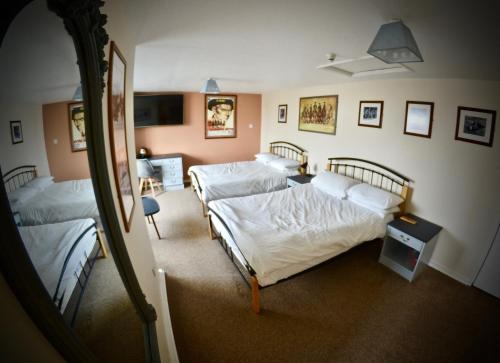 a bedroom with three beds and a mirror at O'Gradys Hotel in Redcar