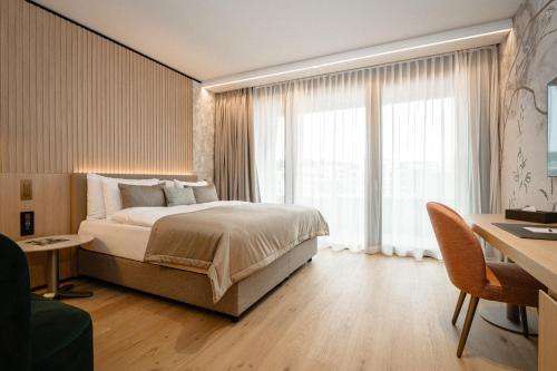 a bedroom with a bed and a large window at Hôtel des Innovations - Hôtel & Appartements - Votre séjour entre Fribourg, ville médiévale et La Gruyère et ses Bains in Marly-le-Grand