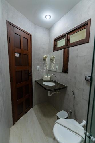 a bathroom with a toilet and a sink and a mirror at Alimar Hotel in Natal