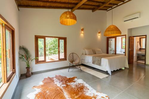 a bedroom with a bed in a room with windows at Casa Xibas e Loft Trancoso in Trancoso