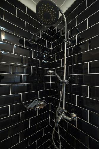 a bathroom with a shower with a black tile wall at KADESE Holiday North Beach Durban in Durban