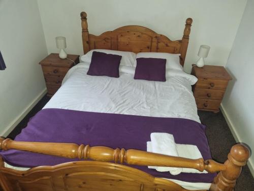 a bedroom with a large wooden bed with purple pillows at Entire 2 bedroom home with parking in Coventry, UK in Coventry