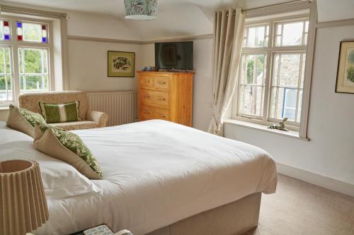 a bedroom with a bed and a chair and windows at Bankes Arms Hotel in Wareham