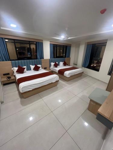 two beds in a large room with windows at Hotel Sun Icon in Vadodara