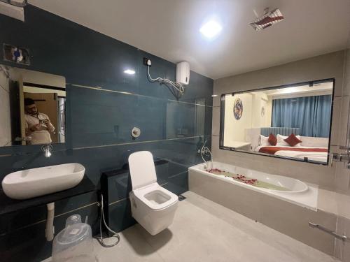 a bathroom with a toilet and a sink and a bed at Hotel Sun Icon in Vadodara