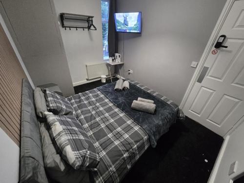 a bedroom with a bed with a couch and a tv at Cog Lane House in Burnley