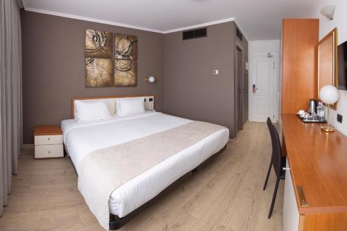 a bedroom with a large white bed and a desk at Best Western Plus Congress Hotel Yerevan in Yerevan