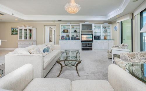 a living room with white furniture and a chandelier at Phoenix East 1401 in Orange Beach