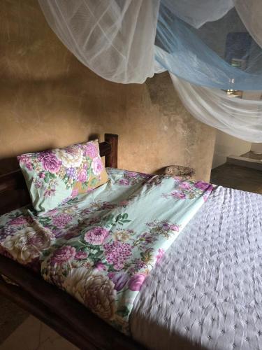 a bed with a floral comforter and two pillows at Paradise Resort in Chabahinga