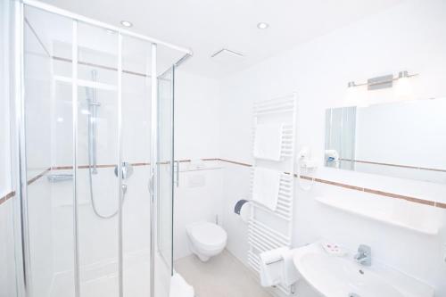 a white bathroom with a shower and a toilet at Gasthof Klement in Isen