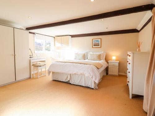 a bedroom with a white bed and a window at Vine Cottage in Halstead