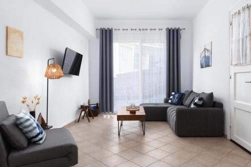 a living room with two couches and a window at Andros Apartments with Free Parking in Steniaí