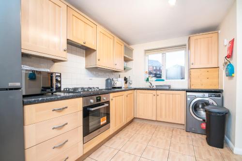 a kitchen with wooden cabinets and a washer and dryer at 6 bed house with free secure parking & 3 bathrooms in Wolverhampton