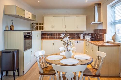 a kitchen with a wooden table and white chairs at Yarm Bank House Apartments in Yarm