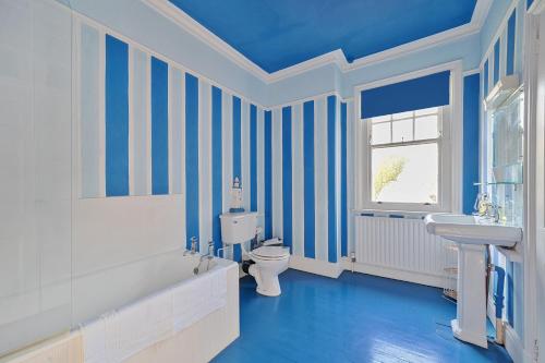 a bathroom with blue and white striped walls and a toilet and sink at Old Ford House in Blandford Forum