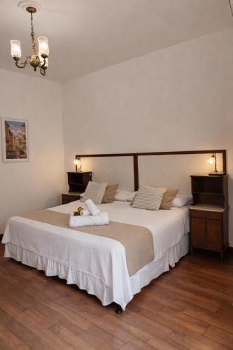 a bedroom with a large bed with white sheets at Panacea Hotel in Villa General Belgrano