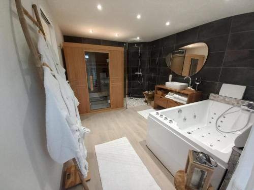 a bathroom with a large tub and a mirror at Domaine la jarrie in La Bussière