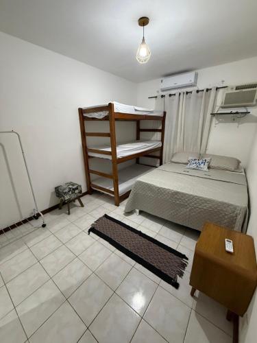 a bedroom with a bunk bed and a table at Refugio arraial in Arraial do Cabo