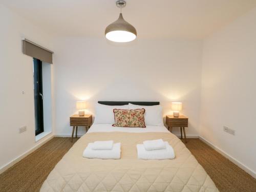 a bedroom with a large white bed with two lamps at 3 The Stoneyard in Bath