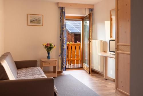 a living room with a couch and a door to a balcony at Cone da Val in San Vigilio Di Marebbe