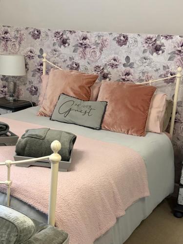 a bedroom with a bed with pink and pink pillows at The Dairyman Suite in Dorchester