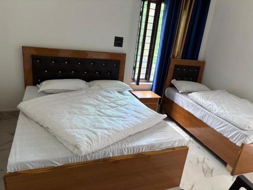 a bedroom with two beds with white sheets at Hotel prayagraj in Barkot