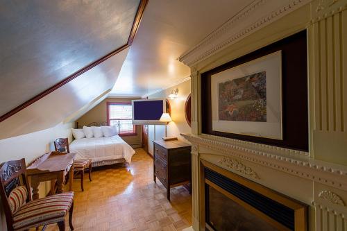 a bedroom with a bed and a living room with a fireplace at Auberge Mr James in Rivière-du-Loup